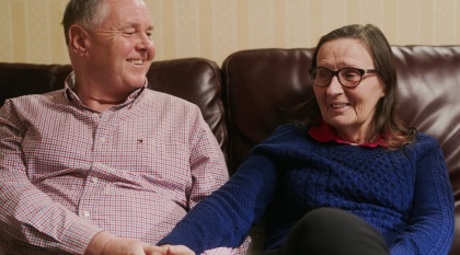 Jo, who has dementia, sits on couch with husband Bill.